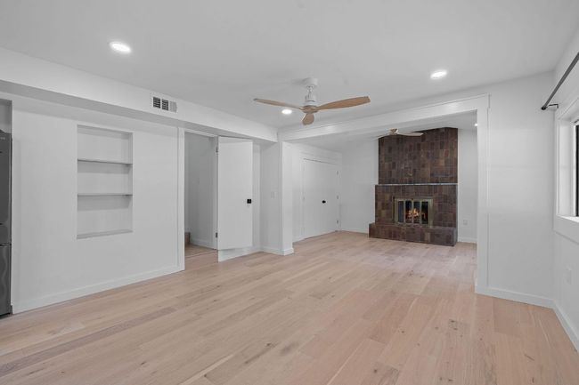 Unfurnished living room with a ceiling fan, light wood-style flooring, built in shelves, a brick fireplace, and recessed lighting | Image 4