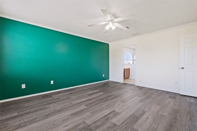 Empty room with crown molding, wood finished floors, a ceiling fan, and baseboards | Image 22