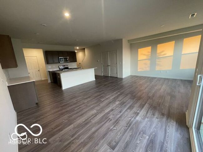 unfurnished living room featuring dark wood-type flooring, visible vents, baseboards, and a sink | Image 9