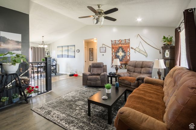 Living area with baseboards, lofted ceiling, wood finished floors, and ceiling fan with notable chandelier | Image 4