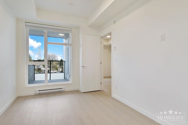 Spare room with baseboards, light wood-type flooring, a healthy amount of sunlight, and baseboard heating | Image 12