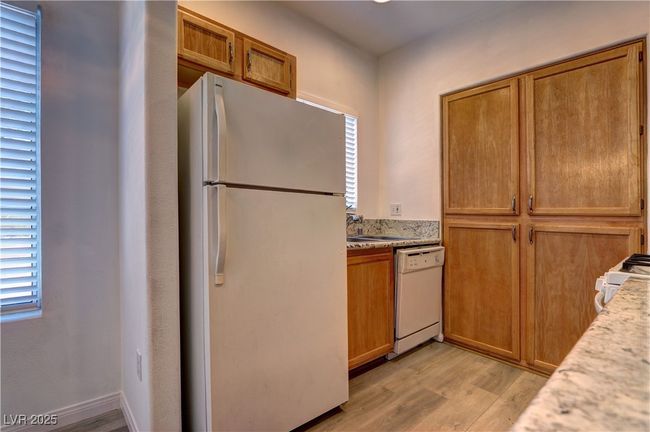Kitchen featuring white appliances, light wood finished floors, brown cabinets, and a sink | Image 7