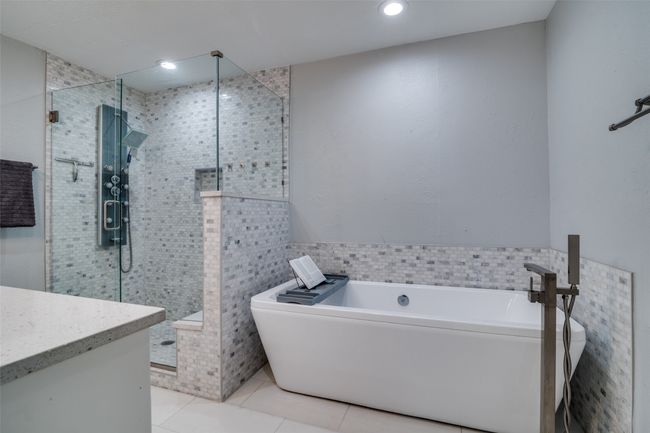 Ensuite bathroom with tile patterned flooring, a freestanding bath, a shower stall, vanity, and tile walls | Image 11