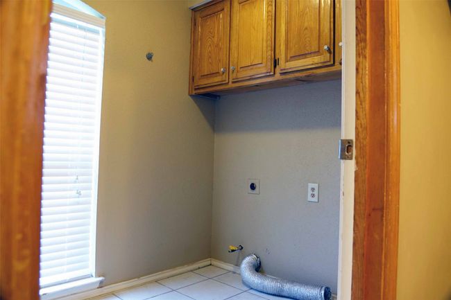 Laundry room featuring cabinet space, light tile patterned flooring, electric dryer hookup, and gas dryer hookup | Image 8