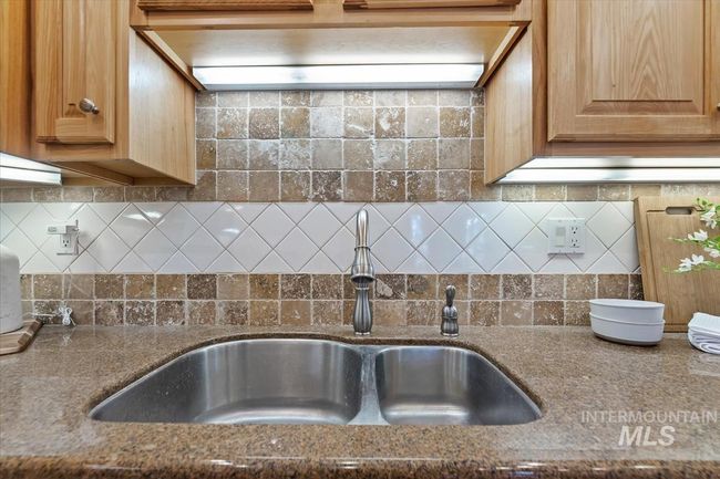 Kitchen view of custom range hood, dark stone counters, and backsplash | Image 23