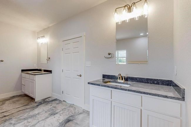 Bathroom featuring two vanities, baseboards, and a sink | Image 19