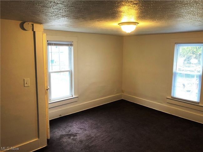 Spare room with dark carpet, a textured ceiling, and a healthy amount of sunlight | Image 14