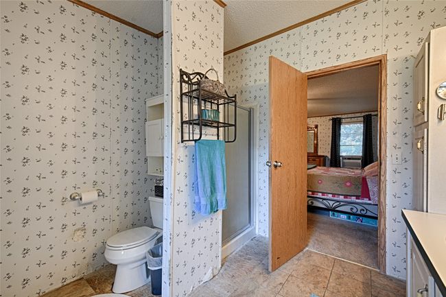 Bathroom featuring wallpapered walls, connected bathroom, vanity, a shower stall, and a textured ceiling | Image 14
