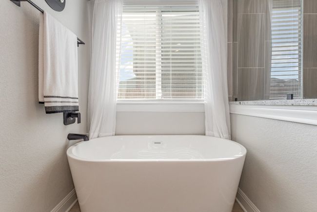Bathroom featuring a freestanding tub, plenty of natural light, and a textured wall | Image 16