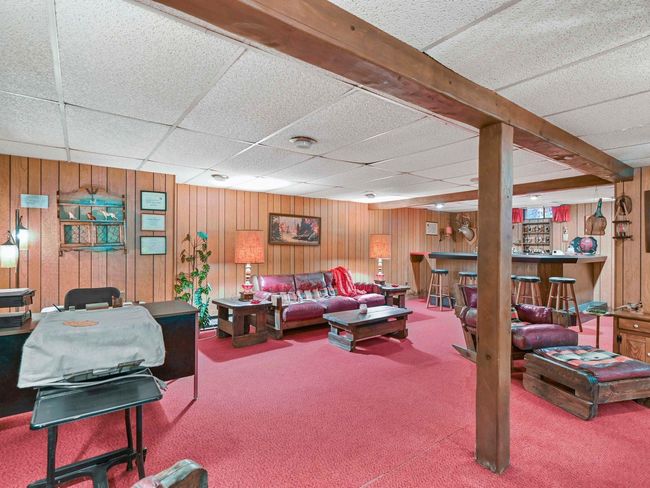 Living room with bar, a paneled ceiling, carpet floors, and wooden walls | Image 31