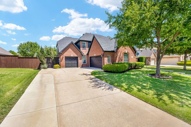 View of front of home with a front yard, a garage, fence, concrete driveway, and brick siding | Image 33