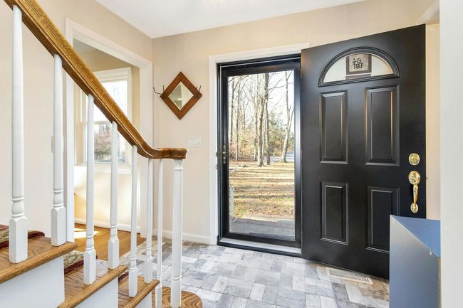 New front door with glass storm door and view of front lawn with mature trees. | Image 12