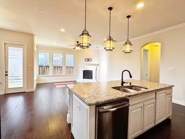 Kitchen featuring stainless steel dishwasher, arched walkways, a kitchen island with sink, open floor plan, and ceiling fan | Image 7