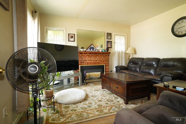 Living room with wood finished floors, healthy amount of natural light, and a fireplace | Image 18