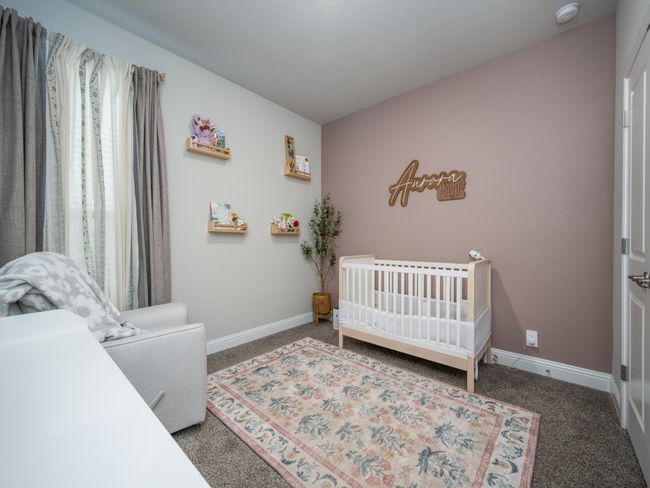 Delightful third bedroom features a soft pink accent wall that adds a touch of warmth and personality. | Image 14