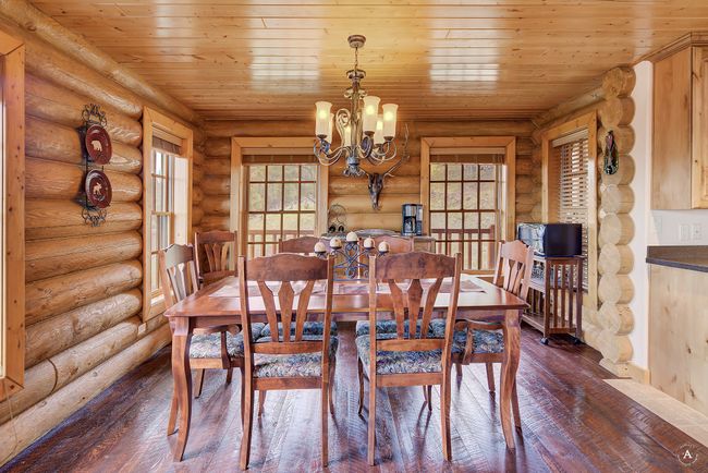 Dining room with dark wood-style floors, rustic walls, a chandelier, plenty of natural light, and wooden ceiling | Image 10