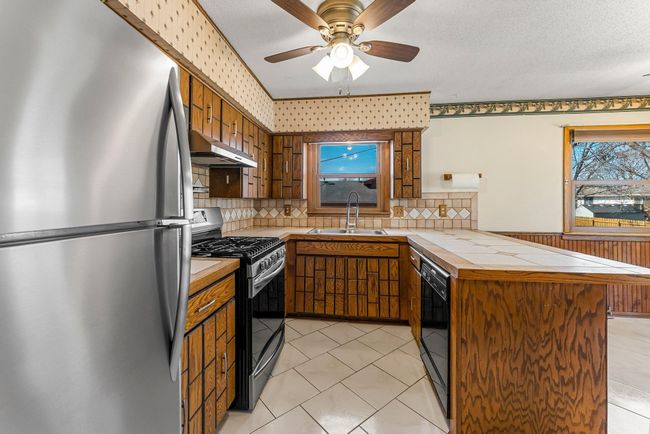 Adjacent to the living room, the kitchen is designed for both style and function, featuring easy-to-maintain ceramic tile flooring, a tile backsplash, and stainless steel appliances. | Image 6