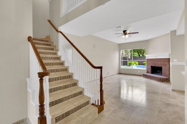 Staircase with tile patterned floors, visible vents, baseboards, a fireplace, and ceiling fan | Image 7