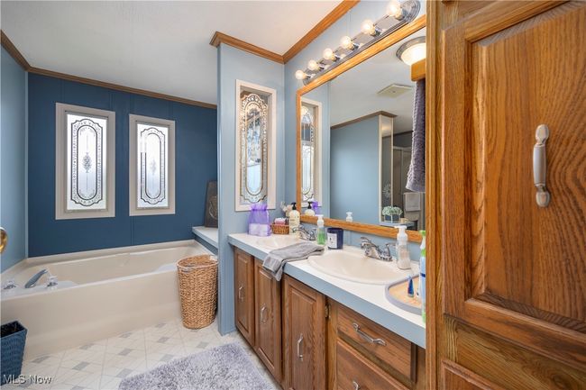 Bathroom featuring double vanity, a bath, ornamental molding, and tile patterned floors | Image 38