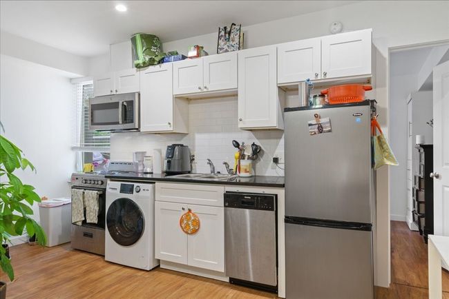 The kitchen boasts stainless steel appliances, elegant cabinetry, and a stylish tile backsplash throughout. | Image 7