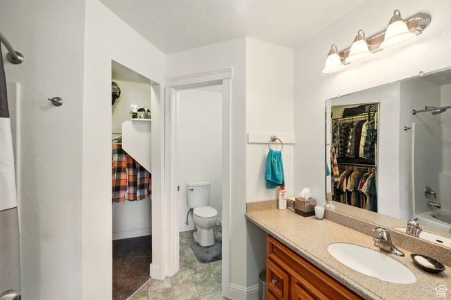 Bathroom with vanity, a spacious closet, toilet, shower combination, and tile patterned floors | Image 16