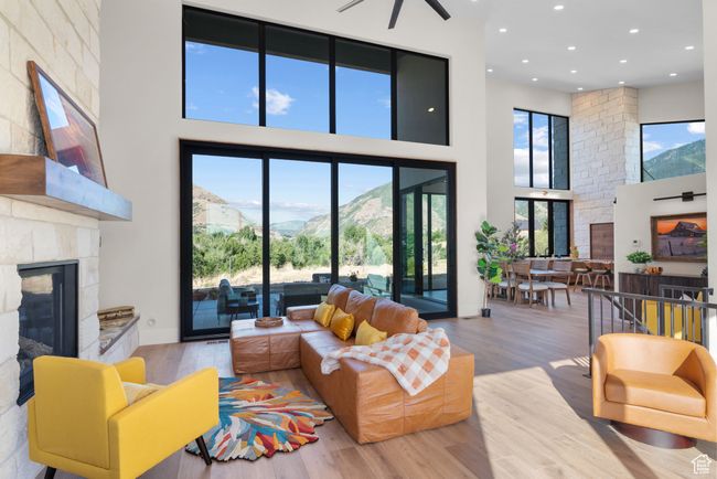 Living room featuring a towering ceiling, a glass covered fireplace, wood finished floors, recessed lighting, and a ceiling fan | Image 10