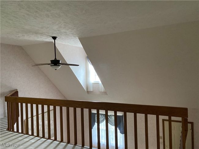 Detailed view of a ceiling fan, a textured ceiling, and a skylight | Image 15