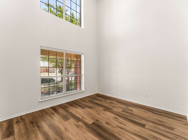 Spare room featuring dark wood-style floors and a towering ceiling | Image 7