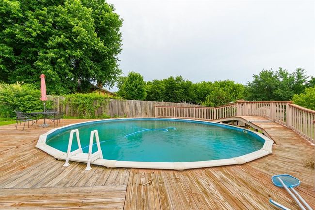 View of swimming pool with a wooden deck and outdoor dining area | Image 35