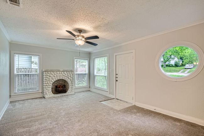 Unfurnished living room featuring a textured ceiling, visible vents, a healthy amount of sunlight, and carpet | Image 5