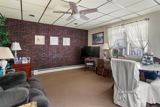 Living room with a baseboard heating unit, a drop ceiling, ceiling fan, and carpet floors | Image 20