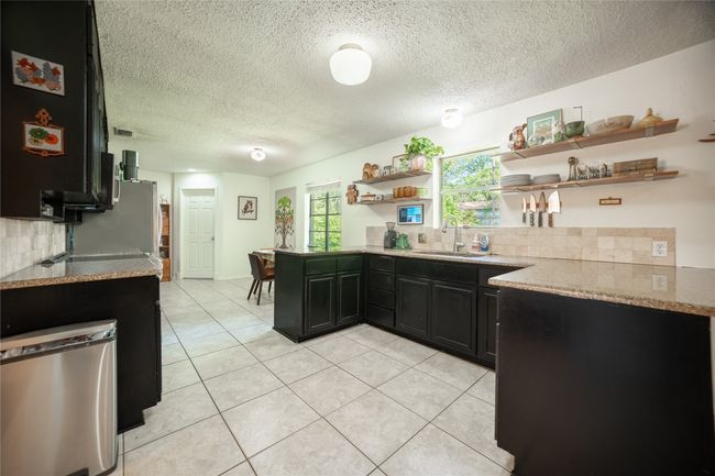 Kitchen featuring a sink, open shelves, a textured ceiling, and decorative backsplash | Image 8