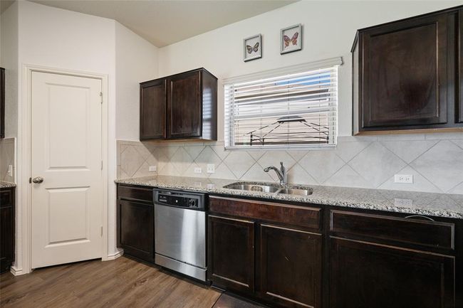 Kitchen with dishwasher, dark wood-type flooring, tasteful backsplash, dark brown cabinetry, and a sink | Image 10