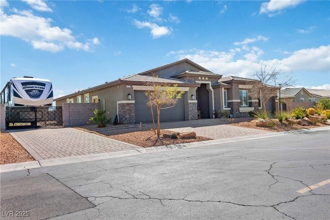 View of front of home featuring stone siding, an attached garage, a gate, fence, and stucco siding | Image 4
