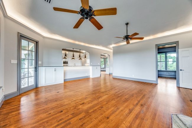 Unfurnished living room featuring a ceiling fan, crown molding, light wood-style floors, and arched walkways | Image 10