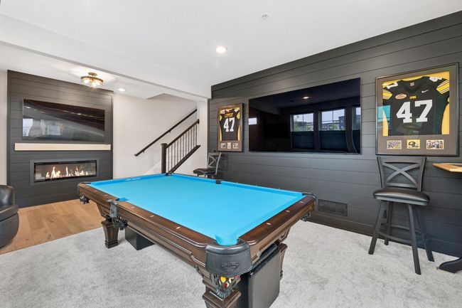 Host game nights or unwind in style in this impressive lower-level entertainment space—featuring a sleek fireplace, custom built-ins, and plenty of room for your favorite games or movie nights. | Image 14