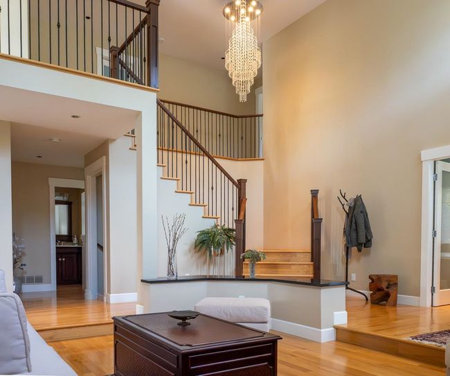 Living room with wood finished floors, stairway, a towering ceiling, and a chandelier | Image 5