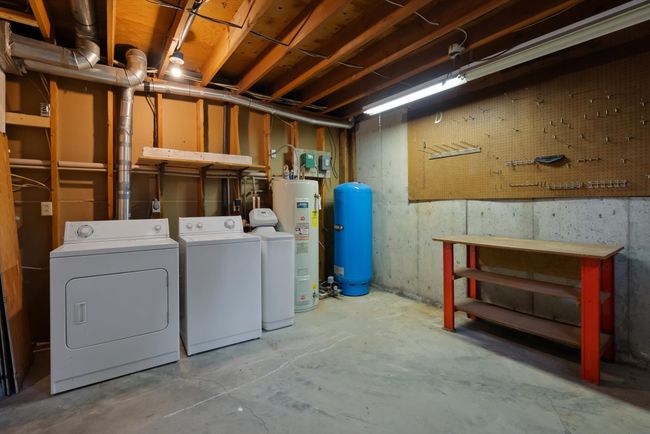 Unfinished basement featuring washer and dryer, a workshop area, and electric water heater, water softener | Image 28