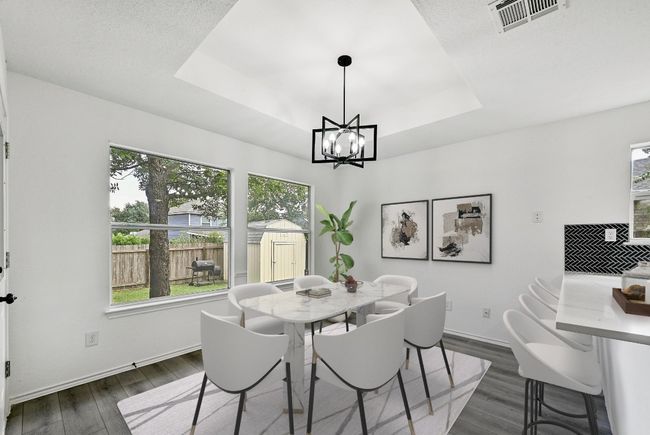 Dining space featuring a tray ceiling, dark wood finished floors, and a chandelier | Image 14