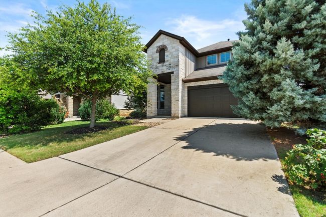 View of front of house with stone siding, concrete driveway, and an attached garage | Image 8