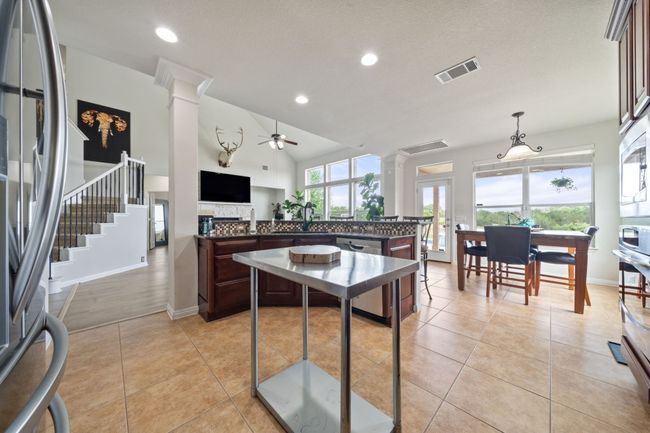 Kitchen with decorative columns, stainless steel appliances, dark countertops, ceiling fan, and recessed lighting | Image 9