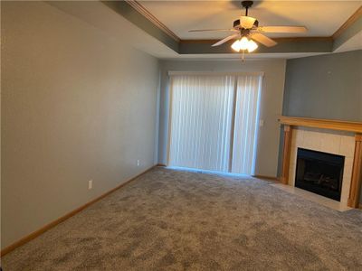 Unfurnished living room featuring crown molding, carpet floors, a fireplace, and ceiling fan | Image 1