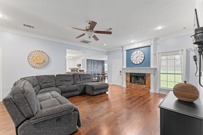 Living area featuring ceiling fan, ornamental molding, wood finished floors, a tile fireplace, and recessed lighting | Image 8