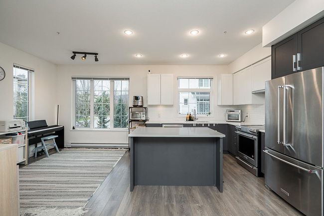 Kitchen featuring premium appliances, a center island, light countertops, decorative backsplash, and a baseboard heating unit | Image 10