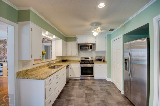 Kitchen featuring light stone counters, crown molding, visible vents, appliances with stainless steel finishes, and a sink | Image 13