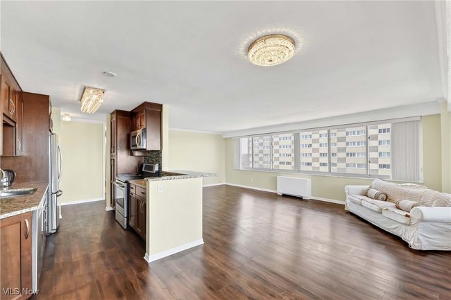 Kitchen featuring open floor plan, appliances with stainless steel finishes, light stone countertops, and dark wood-style flooring | Image 7