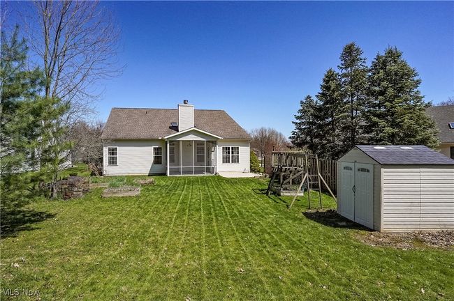 Back of house featuring a chimney, a storage shed, an outbuilding, a lawn, and a sunroom | Image 49