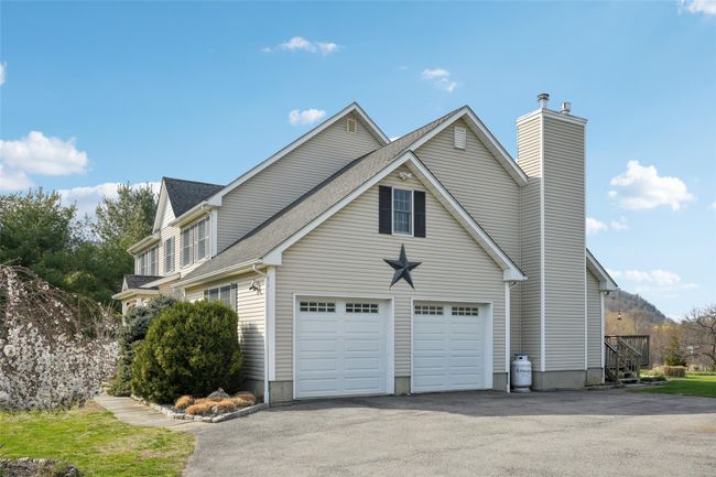 View of home's exterior with a chimney, driveway, and roof with shingles | Image 47