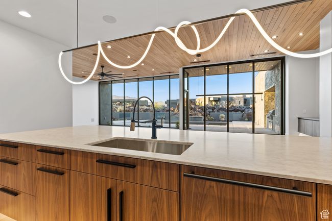 Kitchen with a sink, floor to ceiling windows, brown cabinets, light stone counters, and wooden ceiling | Image 32