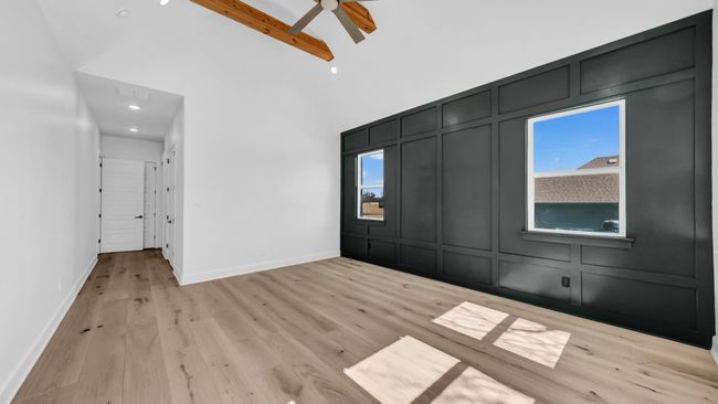 Unfurnished bedroom featuring baseboards, light wood finished floors, a towering ceiling, and a decorative wall | Image 22